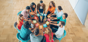 A group of people sitting around a table playing a card game with colorful cards.